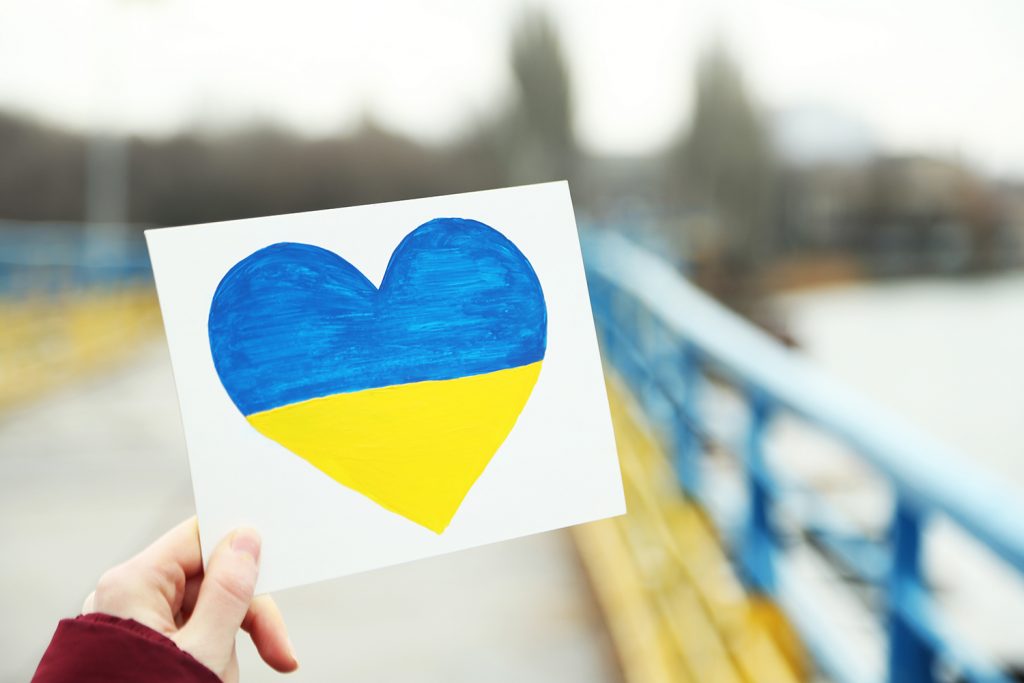 Hand holding paper heart with painted Ukraine flag
